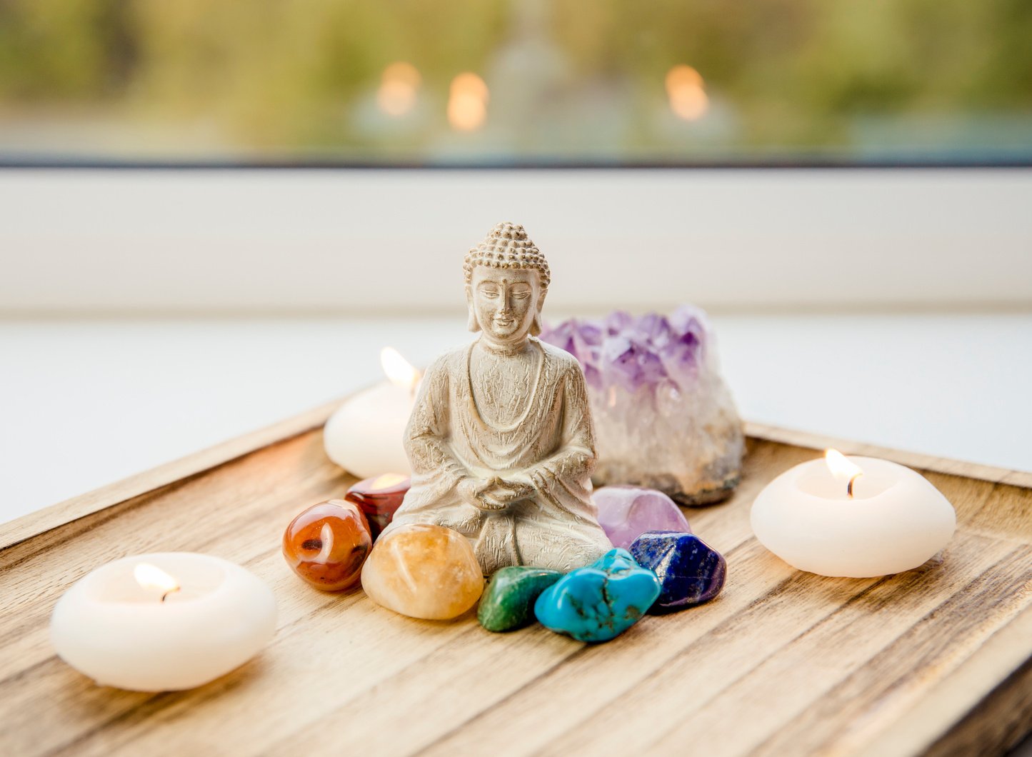 Seven chakra colors crystals stones around sitting Buddha.